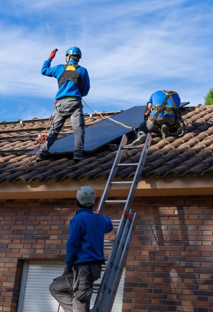 Trois installateurs posant des panneaux solaires photovoltaïques sur une toiture